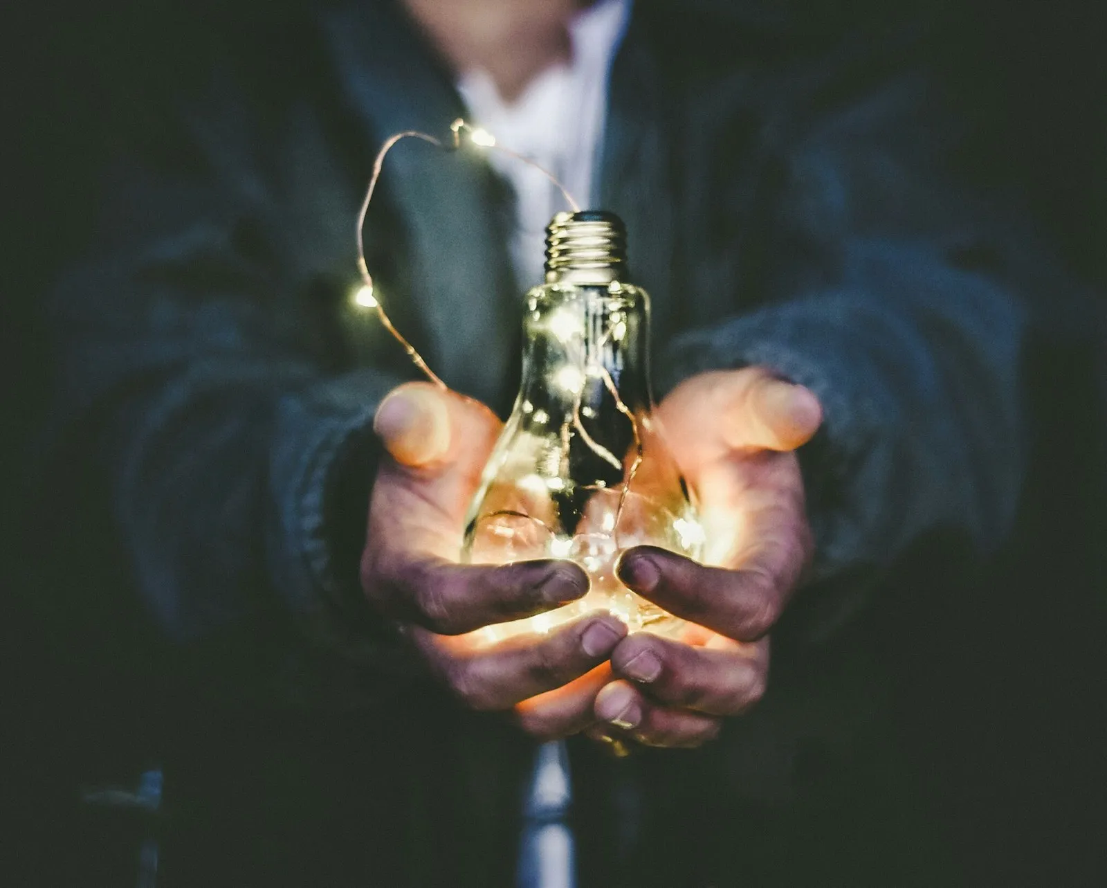 Deux mains tenant une ampoule lumineuse — l'idée mise en lumière